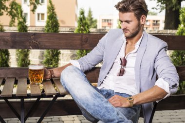 Genç adam bira içiyor.