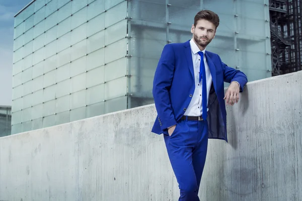Handsome man in a blue suit on the background of the city — Stock Photo, Image