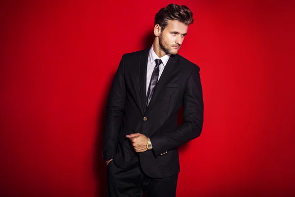 Kırmızı bir arka plan üzerinde siyah bir takım elbise içinde yakışıklı adam