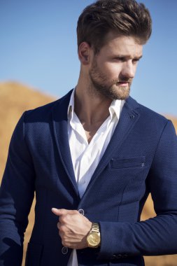 Yakışıklı bir adam çölde karşı koyu mavi ceket