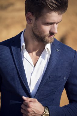 Yakışıklı bir adam çölde karşı koyu mavi ceket