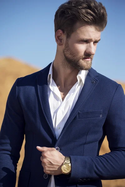 Yakışıklı bir adam çölde karşı koyu mavi ceket