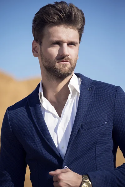 Yakışıklı bir adam çölde karşı koyu mavi ceket