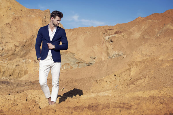 Красивый мужчина элегантно одет, гуляя по пустыне.
