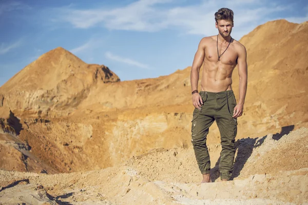 Handsome well-built man walking in the desert