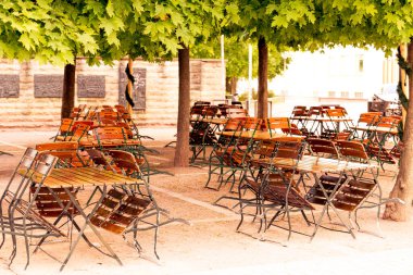 boş masalar ve ağaçların altındaki sandalyeler