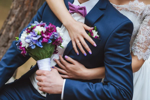 Mariée étreint le marié un bouquet violet bleu — Photo