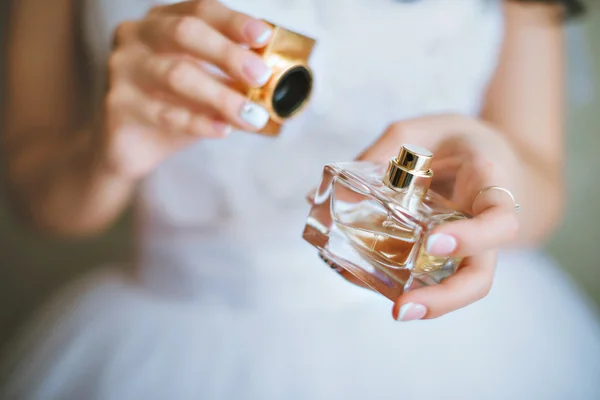 Bride applying perfume on her wrist. The bride is holding perfumes — Stock Photo, Image