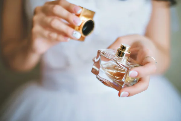 Noiva aplicando perfume no pulso. A noiva está segurando perfumes — Fotografia de Stock