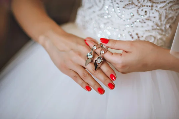 La novia sosteniendo los pendientes de boda. Pendientes de novia plata — Foto de Stock