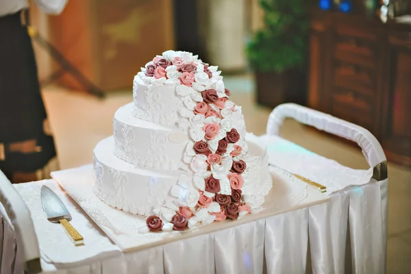 Una novia y un novio están cortando su pastel de bodas con flores moradas y blancas — Foto de Stock