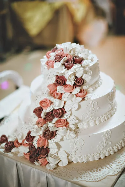 A bride and a groom is cutting their wedding cake with purple and white flowers — Stock Photo, Image