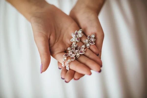 La novia sosteniendo los pendientes de boda. Pendientes de novia plata — Foto de Stock