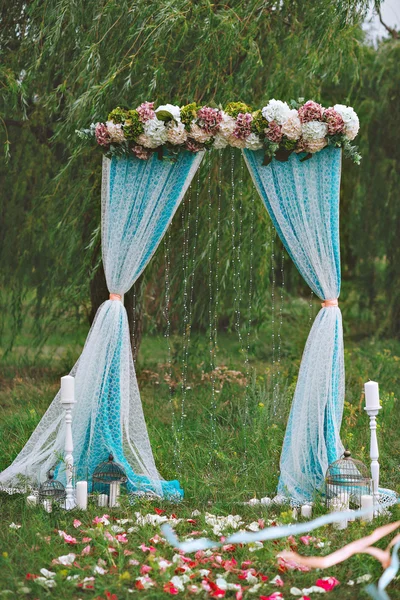 Arco de casamento branco bonito decorado com flores roxas e brancas ao ar livre — Fotografia de Stock