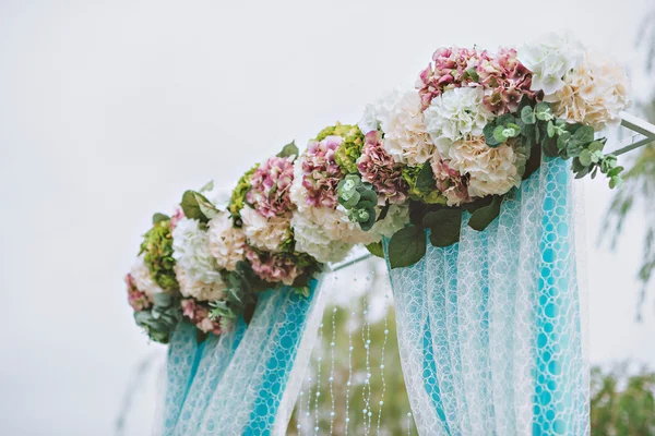 Arco de casamento branco bonito decorado com flores roxas e brancas ao ar livre — Fotografia de Stock