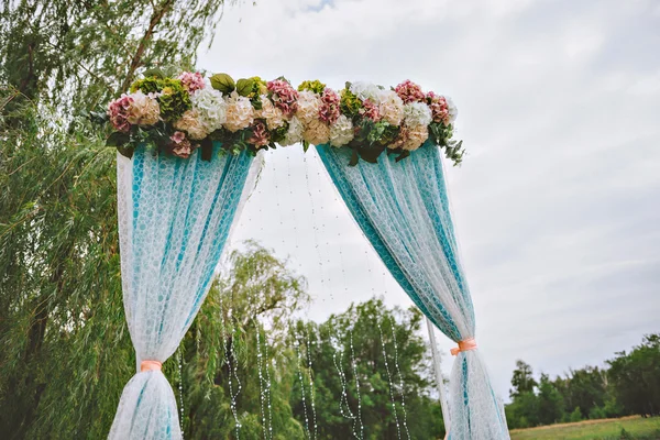 Arco de casamento branco bonito decorado com flores roxas e brancas ao ar livre — Fotografia de Stock