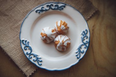 Ev choux krem üzerinde beyaz tabak hazırladım. Ahşap masa üzerinde. Üstten Görünüm. Beyaz bir sır ile. ahşap arka plan üzerinde