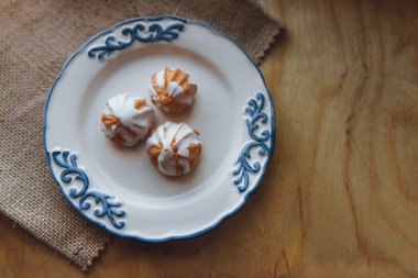 Ev choux krem üzerinde beyaz tabak hazırladım. Ahşap masa üzerinde. Üstten Görünüm. Beyaz bir sır ile. ahşap arka plan üzerinde