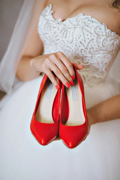 Fotografía de una novia irreconocible sosteniendo zapatos rojos de boda — Foto de Stock