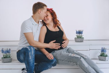 Gebelik. Bir adam hamile bir kadını öper. Koca elini karnında tutuyor. Müstakbel ebeveynler. Bir mucize bekliyorum