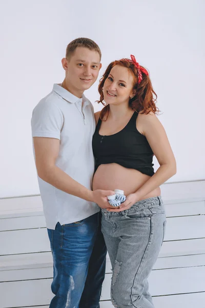 Un jeune homme et une jeune belle femme se regardent. En prévision du bébé. Femme enceinte aux cheveux roux. Bottes sur son ventre . — Photo