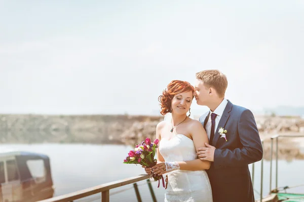 Retrato de casal amoroso feliz, perto da costa, sorrir, comunicar, rir. Nas mãos Buquê nupcial com flores brancas, roxas, rosa . — Fotografia de Stock