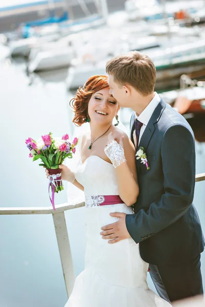 Porträtt av lyckliga älskande par, nära stranden, smile, kommunicera, skratta. I händerna brudbukett med vita, lila, rosa blommor. — Stockfoto