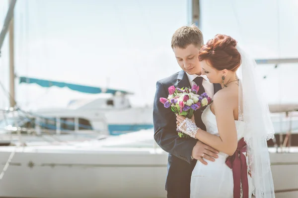 La pareja en el puerto, abrazándose, mirando el ramo . — Foto de Stock