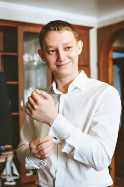 Adam kol düğmeleri kapatır. Beyaz gömlek