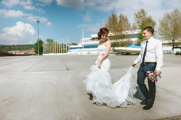 Frischvermählte spazieren, der Bräutigam hält ein weißes Brautkleid in der Hand — Stockfoto