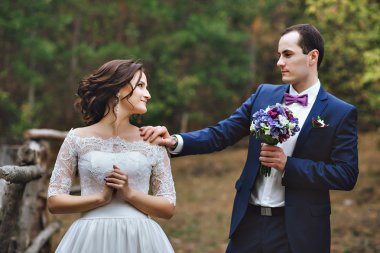 Damat gelini bakar, onu arkasında, eşi omzuna dokunur. O döner ve ona bakar. Dantel elbise ön planda, ormanın içinde müstakbel karım. O döner ve ona bakar.