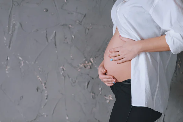 Kobieta w ciąży w białym mans koszula, portret. Szare ściany. Patrzy w dół. Tam jest miejsce dla tekstu — Zdjęcie stockowe