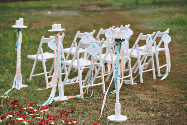 Beautiful wedding set up. wedding decor on the lawn, wedding arch, chairs with ribbons. turquoise, purple and white. The rose petals on the ground. Wedding ceremony