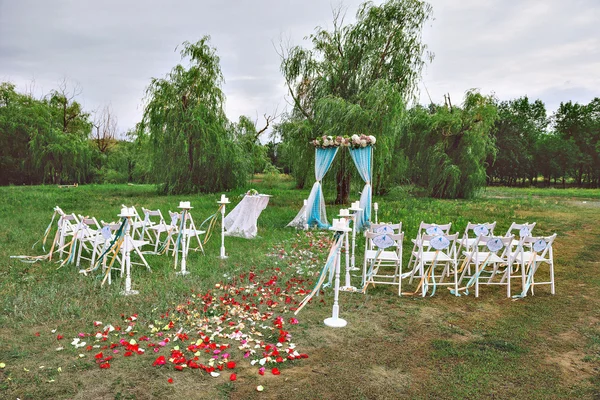 Beautiful wedding set up. wedding decor on the lawn, wedding arch, chairs with ribbons. turquoise, purple and white. The rose petals on the ground. Wedding ceremony