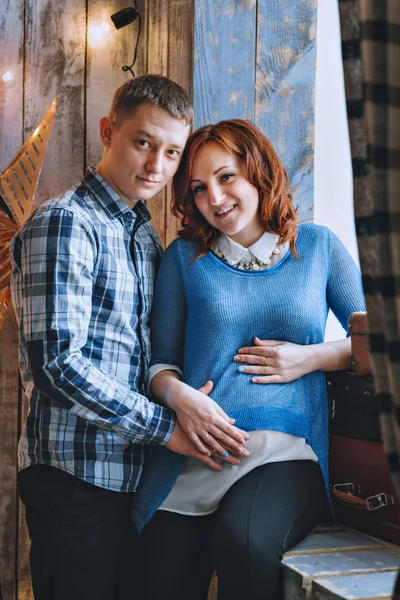 Jovem e mulher grávida sentados na janela. Felicidade familiar, em antecipação ao bebê — Fotografia de Stock