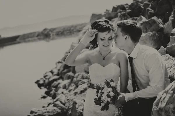 Happy leende unga bruden och brudgummen, promenader på stranden, kyssar, kramar bröllopsceremoni nära klipporna, ocean. — Stockfoto
