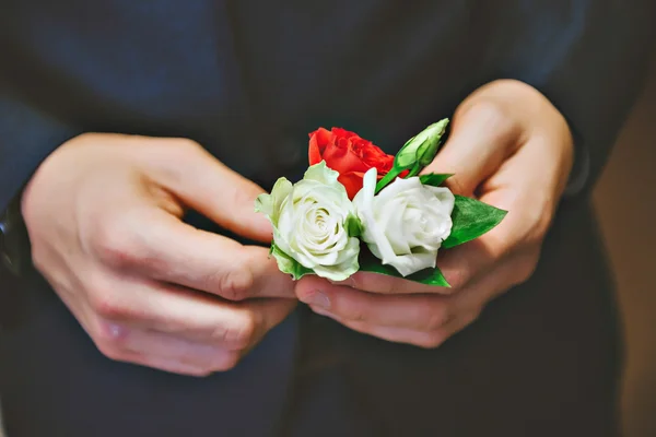 Mens Mavi takım, kırmızı kravat, beyaz gömlek. Damat onun yaka çiçeği gül ayarlar.