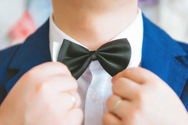 El hombre usa púrpura, púrpura pajarita. El novio va a la boda. Mañana de bodas. El hombre endereza su corbata . — Foto de Stock