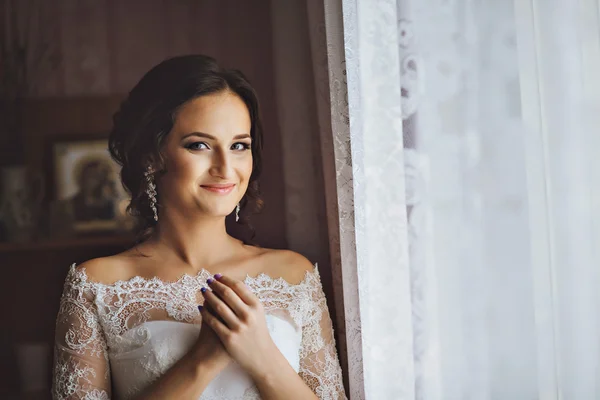 白いウェディング ドレスで顔の近くに手で若いブルネットの美人花嫁の肖像画. — ストック写真