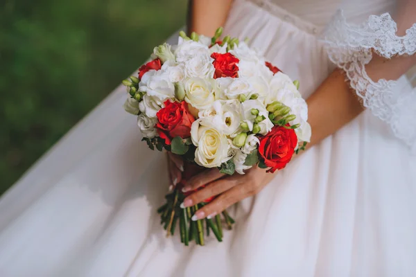 Buquê de noiva flores brancas vermelhas nas mãos da noiva — Fotografia de Stock
