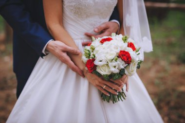 Yeni evliler, elinde gelin buketi kırmızı beyaz çiçekler