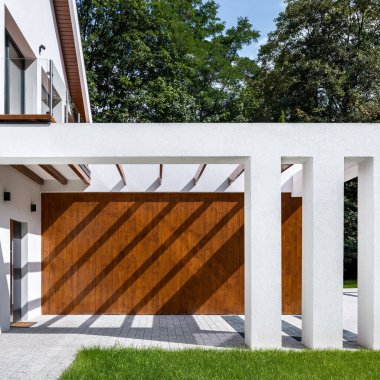 Ahşap duvarlı, dekoratif sütunlu ve tavanda ahşap tahtalarla modern evin dış görünüşü.