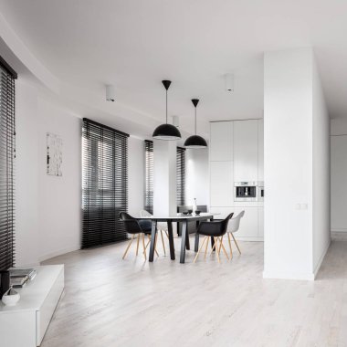 Modern siyah-beyaz yemek alanı, geniş mutfağında masa ve sandalyeler kıvrımlı duvarlı siyah-beyaz daire, kıvrımlı duvar ve uzun siyah pencere perdeleri.
