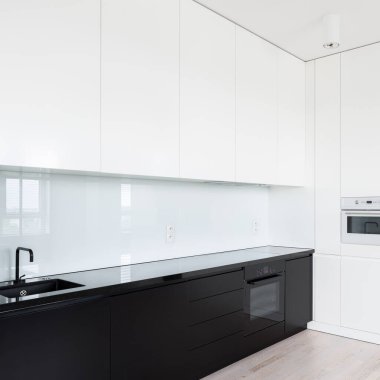 Basit ve zarif siyah-beyaz mutfak. Bir sürü çekmecesi, dolabı ve cam fıskiyesi var.