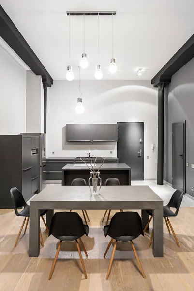 Kitchen in loft apartment with gray furniture, modern gray dining table and black pillars
