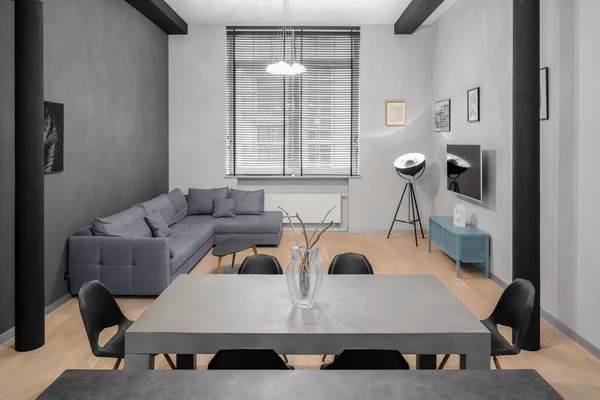 Small living room in loft style apartment and modern dining table with six chairs