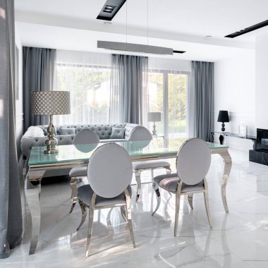 Süslü, cam yemek masası ve beyaz oturma odasında mermer döşemeli büyüleyici sandalyeler.