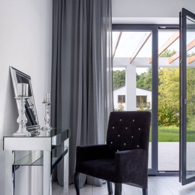 Ayna ve dekoratif şamdanlarla süslü gümüş makyaj masası ve zarif, yorgan kaplı sandalye.