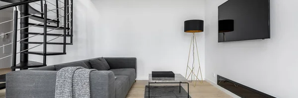 Panorama of minimalist living room with big television screen and industrial style staircase