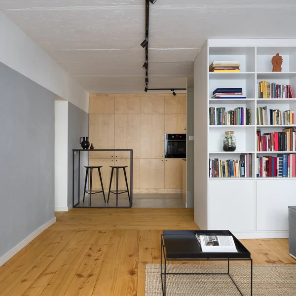 Small apartment with kitchen open to living room with exposed concrete on ceiling and walls and wooden floor